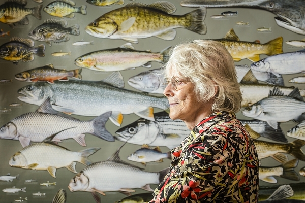 Elliot with the poster she created that features life-size illustrations of every fish species in the state of Wisconsin. The poster hangs outside her office in Nolan Hall at the University of Wisconsin. (Photo by Bryce Richter/UW-Madison)