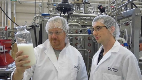 Scientists at Purdue looking at a jar of milk.