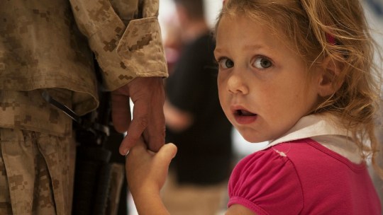 A young girl holds a soldier's hand