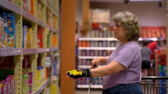 Penn State IT specialist Michelle McManus uses the Third Eye Project's glove cam to help her make a selection at a grocery store.