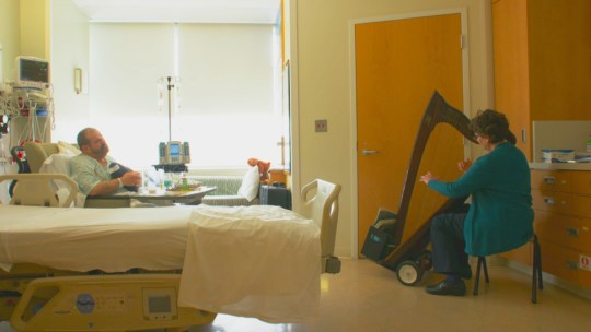 A certified musician performs in a University of Michigan hospital patient's room as part of the Gifts of Art program