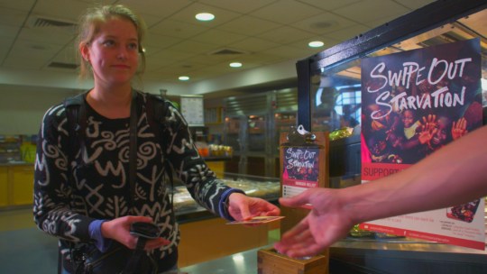 A Purdue University student purchases a Swipe Out Starvation card in a dining hall.