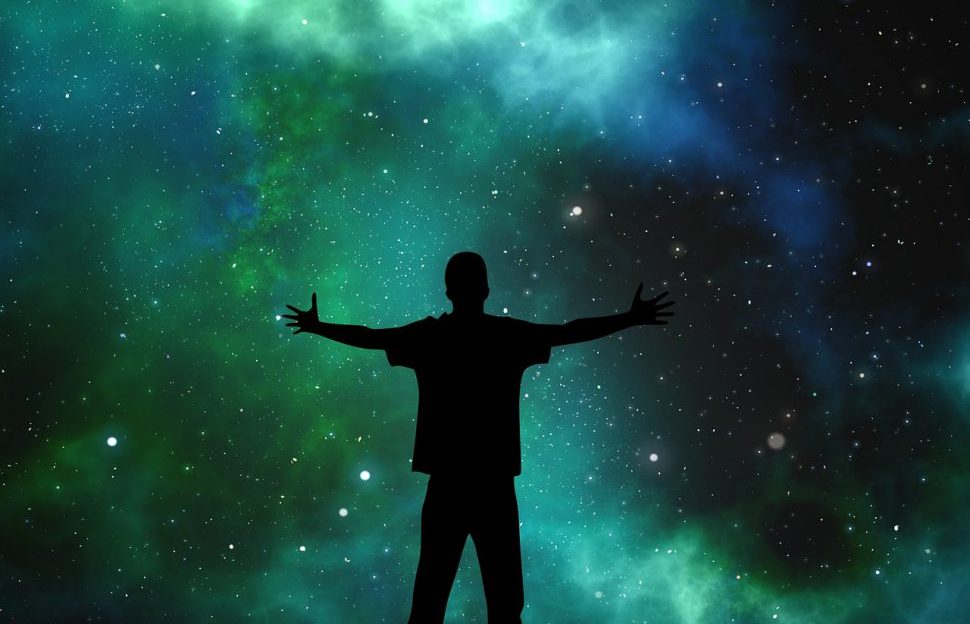 A silhouette of a person standing in front of a shot of the universe.