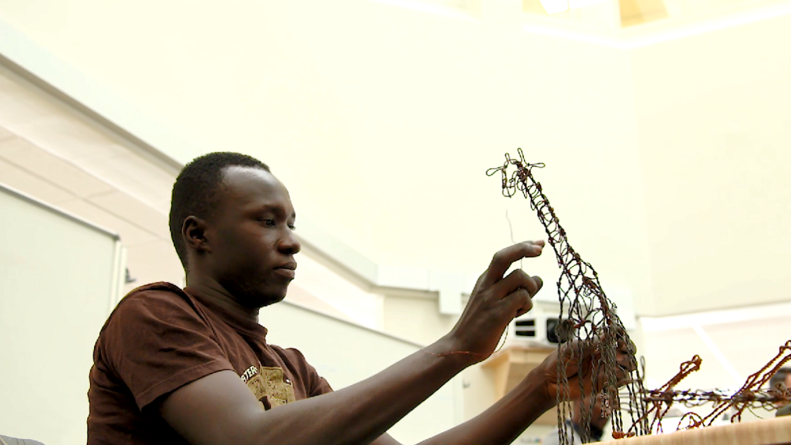 An artisan from Michigan State University's Snares to Wares Initiative crafts a giraffe sculpture from wire that was once a snare for poaching