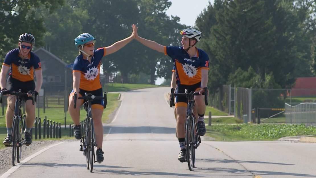 University of Illinois Illini 4000 riders high-fiving while riding their bikes