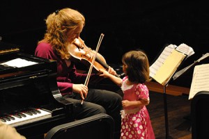 A child touches a violin during a Michigan State University Sensory Concert